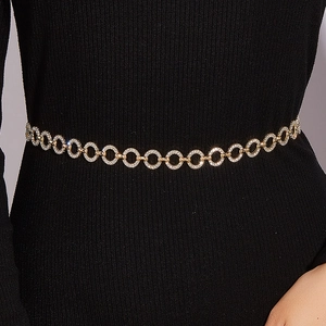Close-up of golden rhinestone chain belt on black dress with detailed metal ring links
