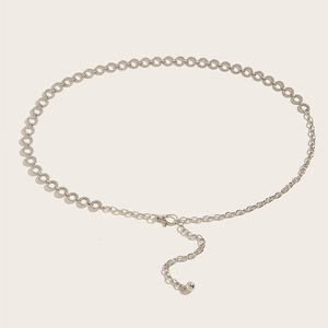 Detail view of silver metal waist chain with ring links and ball pendant charm