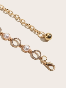 Detail of gold metal waist chain with imitation pearls and rhinestone rings
