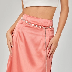 Detailed close-up of sparkling rhinestone chain belt on pink satin skirt with lobster clasp