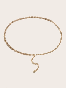 Gros plan sur la chaîne de taille dorée avec strass, maillons et pendentif boule