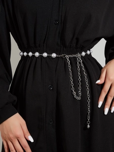 Détail d'une ceinture chaîne argentée avec franges et perles blanches élégantes