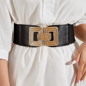 Wide elastic black waist belt with decorative gold geometric buckle on white dress