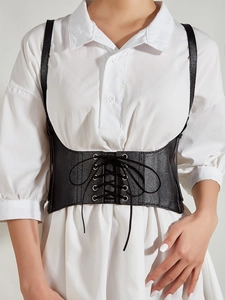Close-up of black leather lace-up corset belt with metal eyelets and thin shoulder straps