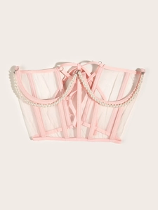 Détail du corset en mesh rose avec chaînes de perles blanches et rubans lacés au dos