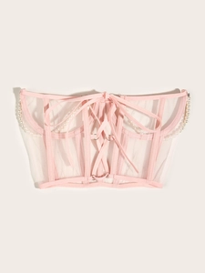 Détail d'un haut corset en mesh rose avec laçage frontal et bordure en perles