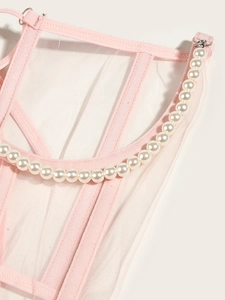 Détail de ce haut corset en mesh rose orné de perles blanches le long du décolleté
