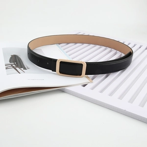 Women's black leather belt with gold rectangular buckle shown on a fashion magazine background