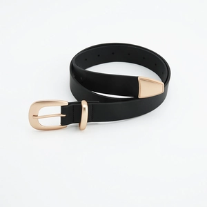Detail of slim black leather belt with matte gold buckle and fine grain texture