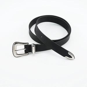 Detail of vintage carved silver buckle and metal tip on slim black waist belt