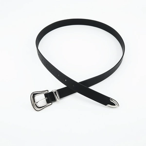 Detail of slim black leather belt featuring ornate western style silver buckle and tip