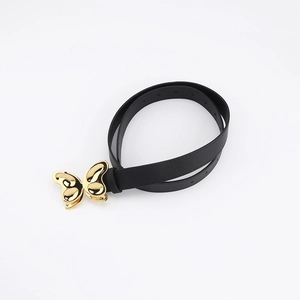 Détail de la ceinture en similicuir noir avec boucle papillon en métal doré poli