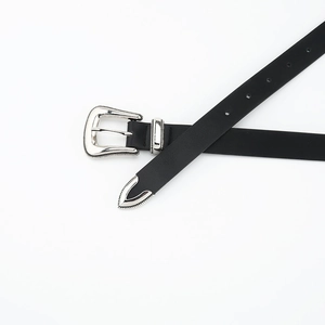 Detail of black thin belt featuring western style silver floral engraved buckle and tip