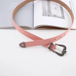 Close-up of pink slim belt with vintage engraved silver buckle on a fashion magazine