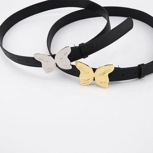Détail de ceintures noires avec boucles papillon dorées et argentées sur fond blanc