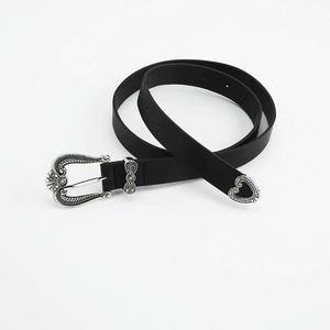 Detail of vintage black leather belt with silver western carved buckle and tip