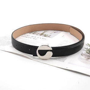 Close-up of black leather belt with unique silver S-shaped buckle on a magazine
