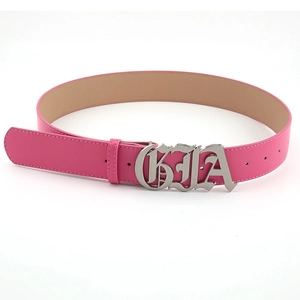 Détail de la ceinture en cuir rouge rose avec grande boucle en métal à lettres évidées