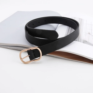Detail of black matte leather belt with engraved rose gold D-ring buckle on magazine