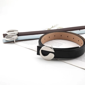 Close-up of minimalist leather belts in black, blue and brown with silver metal buckles