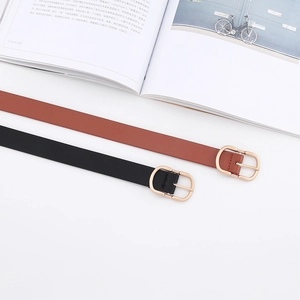 Detail view of slim leather belts in black and reddish brown with golden D-shaped buckles
