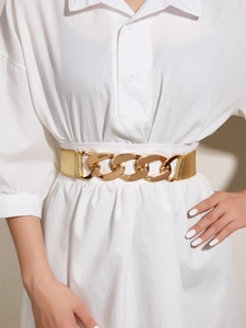 Detail of gold metal chunky chain link belt on white dress for waist cinching