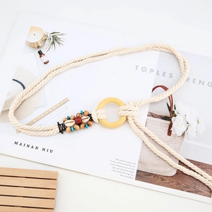 Dettaglio di cintura intrecciata boho con anello di legno, perline e conchiglie