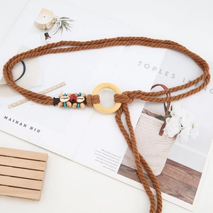 Dettaglio della cintura intrecciata boho con anello di legno, conchiglie e perle