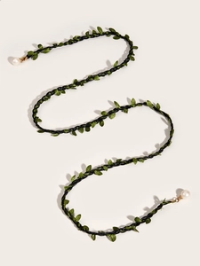 Detail of hand-woven black cord waist chain with green leaf charms and white pearls