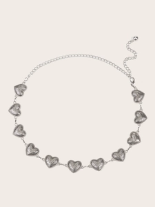 Detail of silver heart-shaped metal waist chain with vintage engraved patterns and lobster clasp