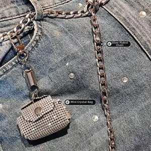 Close-up of sparkling crystal mini bag charm with silver-plated chain on denim