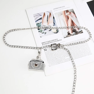 Detail of silver chain belt with shimmering rhinestone bag pendant on fashion magazine