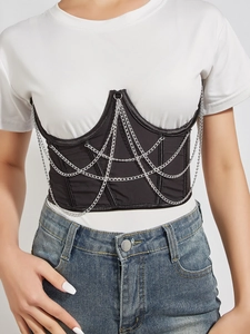 Detail of a black corset belt with layered silver chains over a white t-shirt outfit