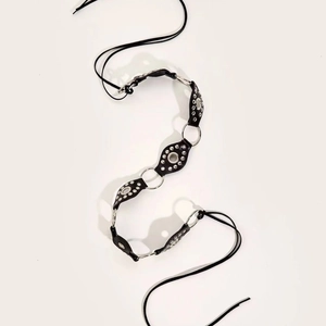 Y2K punk style black waist belt with metal eyelets and silver rings on beige background