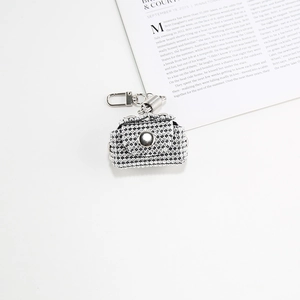 Macro shot of silver rhinestone mini bag charm for women on white magazine background