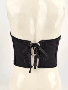 Detail of lace-up back design on a black corset belt with metal rings and satin ribbons