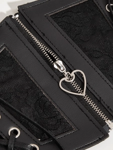Detail of heart-shaped silver zipper pull and delicate lace on black corset belt