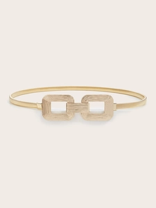 Detail view of gold elastic metal waist belt with textured interlocking rectangular buckle