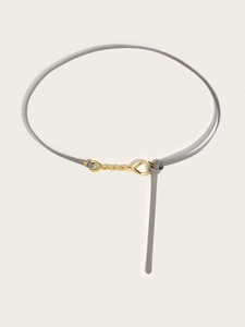 Detail of grey slim leather waist belt featuring a spiral gold metallic buckle for dresses