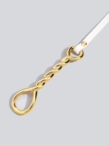 Detail of white slim leather belt with a decorative twisted gold metal buckle and stud