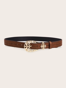 Detail of vintage brown embossed leather belt with ornate golden floral buckle design
