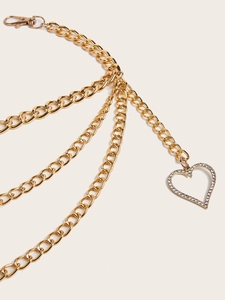 Detail of layered gold metal waist chain featuring a sparkling rhinestone heart pendant