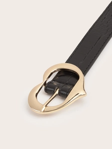 Détail de la boucle dorée en forme de cœur sur une ceinture noire en cuir croco