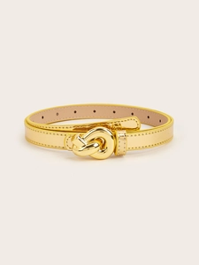 Detailed macro view of a thin gold leather belt with a stylish metallic knot-shaped buckle