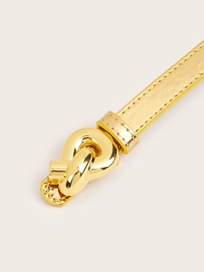 Close-up of a glossy gold belt with a polished metal twist-knot buckle and neat stitching