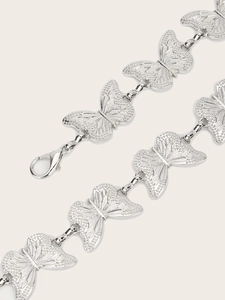 Detailed macro view of silver butterfly chain links with textured engraving and lobster clasp
