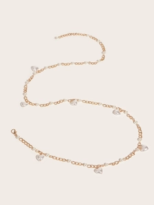 Détail d'une ceinture chaîne dorée ornée de perles blanches et de pendentifs en forme de cœur