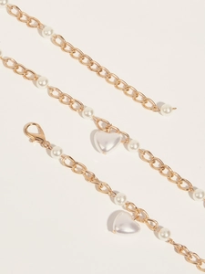 Détail de la ceinture chaîne dorée avec perles blanches et pendentif en forme de cœur