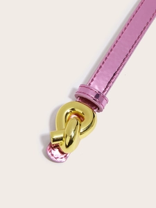 Detail of pink patent leather skinny belt with a gold knot-shaped metal buckle closeup