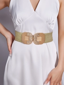 Close-up of golden wide elastic waist belt with hammered metal buckle on white dress